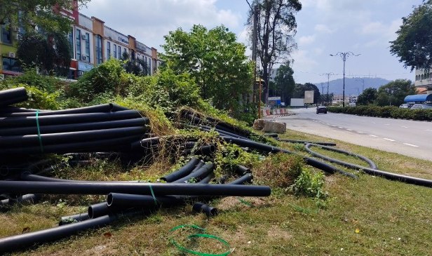 'Bahan binaan ditinggalkan di tepi jalan cemar pemandangan ke Teluk Cempedak' - Pengguna